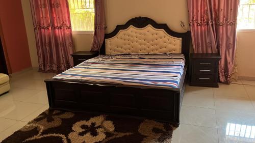 1 cama grande en un dormitorio con cortinas y alfombra en Berakah cozy Rentals, en Freetown