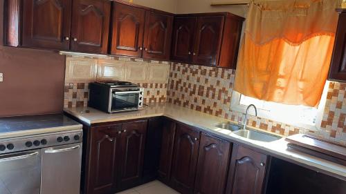 a kitchen with wooden cabinets and a sink and a microwave at Berakah cozy Rentals in Freetown