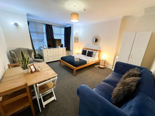 a living room with a blue couch and a bed at Cosy Apartments Near Hampstead Heath With Free On-Site Parking & Private Gardens, Golders Green in London