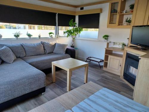 a living room with a couch and a tv at Stacaravan 14 met airco vakantiepark de Tien Heugten Schoonloo Drenthe in Schoonloo