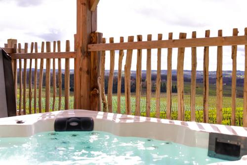 bañera de hidromasaje frente a una valla de madera en Le Domaine de La Tour des Vents en Bergerac