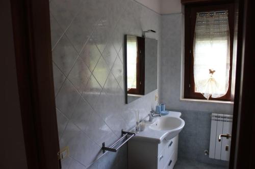 a white bathroom with a sink and a mirror at Appartamento e giardino Perugia in Deruta