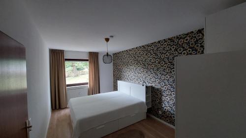 a bedroom with a white bed and a patterned wall at Fewo Silberborn - Weserbergland (Fam. Oehler) in Holzminden