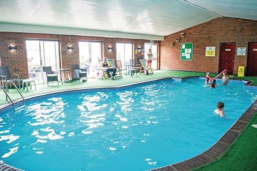 a large swimming pool in a building with people in it at Harries Lodge ocean in New Quay