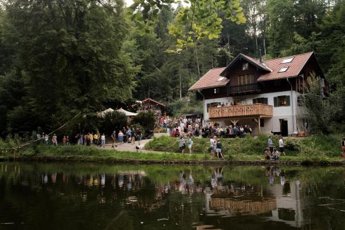 a group of people standing outside a building next to a lake at Waldschlucht in Bad Kohlgrub