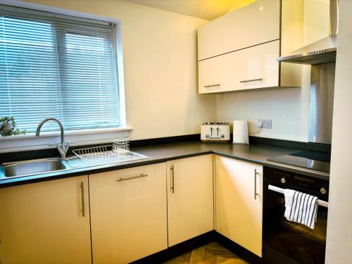 uma cozinha com armários brancos, um lavatório e uma janela em The Grange em Stockton-on-Tees