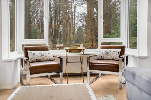 two chairs and a table in a room with windows at 3 bed house near Gatwick and Redhill in Bletchingley