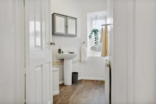 a white bathroom with a sink and a tub at 3 bed house near Gatwick and Redhill in Bletchingley