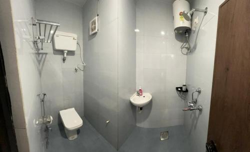 a white bathroom with a toilet and a sink at HOTEL DADO'S INN in Panaji
