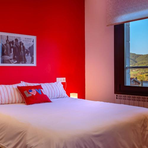 1 dormitorio con cama blanca y pared roja en Apartamentos Naredo, en Villaviciosa