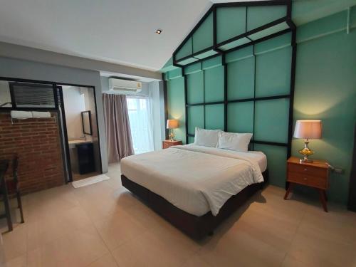a bedroom with a large bed with green walls at Qoo Hotel in Buriram