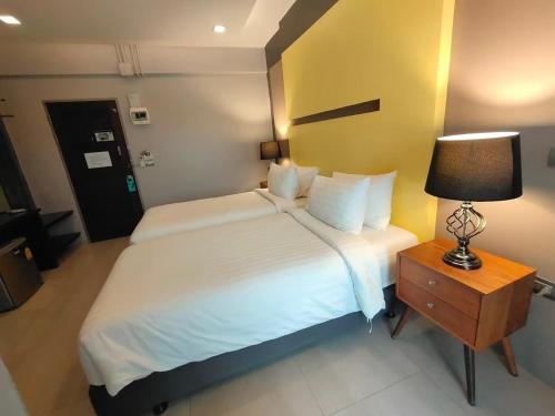 a hotel room with a bed and a lamp on a table at Qoo Hotel in Buriram