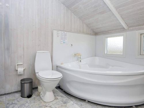 a white bathroom with a tub and a toilet at 6 person holiday home in Hemmet in Falen