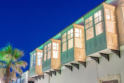 a building with windows and a palm tree at Cumbalıca Beach Hotel in Cesme