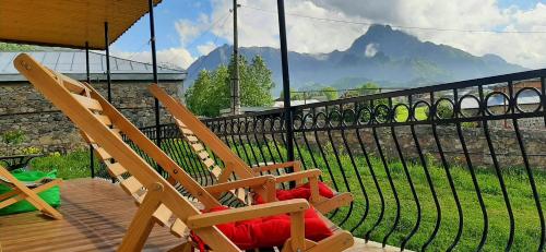 two wooden chairs sitting on a deck with a view of a mountain at Hotel Garbani in Stepantsminda