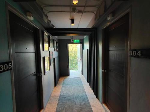 a hallway with a long corridor with black doors at Qoo Hotel in Buriram