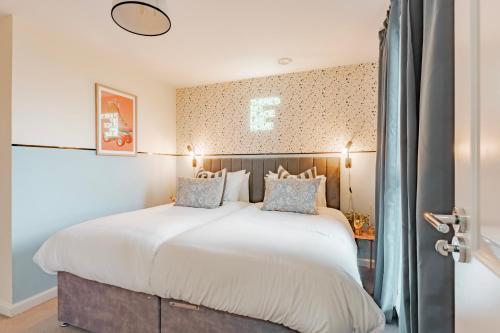 een slaapkamer met een groot wit bed met blauwe kussens bij Stylish & Spacious 3bed Home with Fast Wifi & Private Parking in Cambourne