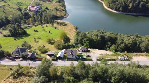 an aerial view of a house on a hill next to a lake at Cabana Baraj Apuseni Mountains in Mihoeşti