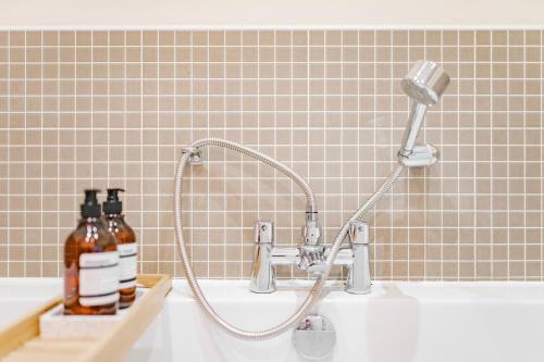a shower head on a sink in a bathroom at Stylish & Spacious 3bed Home with Fast Wifi & Private Parking in Cambourne