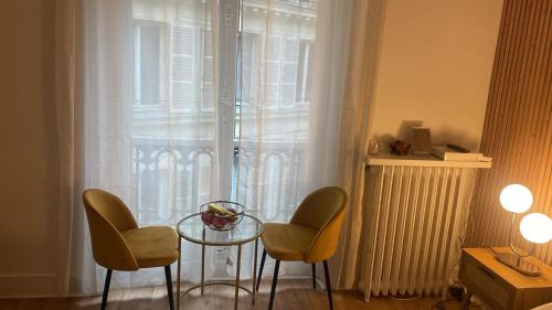 een kamer met een glazen tafel, 2 stoelen en een raam bij Studio opéra paris in Parijs