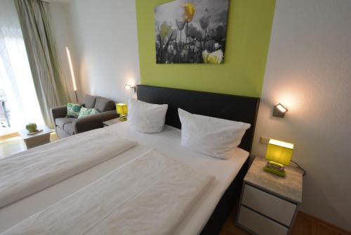 1 dormitorio con cama blanca y pared verde en Modernes 1-Zimmer-Appartement im Kurgebiet von Bad Kreuznach, en Bad Kreuznach