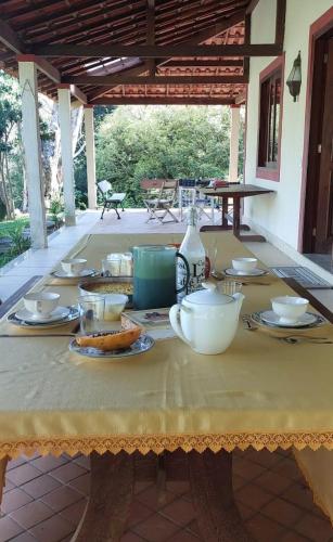 uma mesa com pratos e tigelas numa toalha de mesa amarela em Fazenda Santa Luzia em Além Paraíba