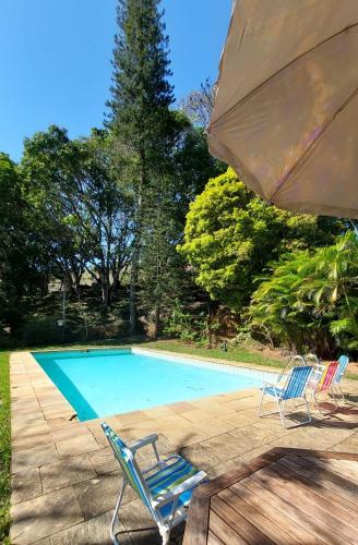 uma piscina com duas espreguiçadeiras e um guarda-sol em Fazenda Santa Luzia em Além Paraíba