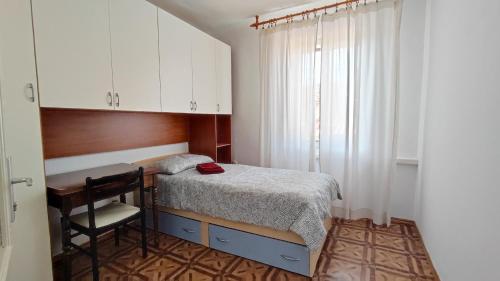a small bedroom with a bed and a desk at Altana Rooms in Koper