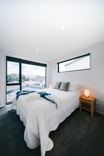 a white bedroom with a large bed and a window at The little Gem at Merivale -1km to Central city in Saint Albans