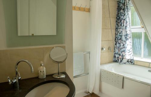 a bathroom with a sink and a tub and a mirror at Stationmasters Lodge in Stromeferry