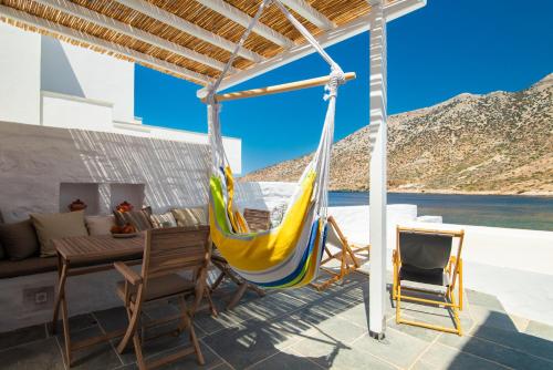 a hammock on a patio with a table and chairs at Stunning Sunset House on Kamares Bay with Playground in Kamarai