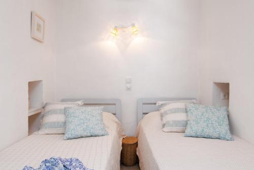 two beds in a bedroom with white walls and blue pillows at Stunning Sunset House on Kamares Bay with Playground in Kamarai