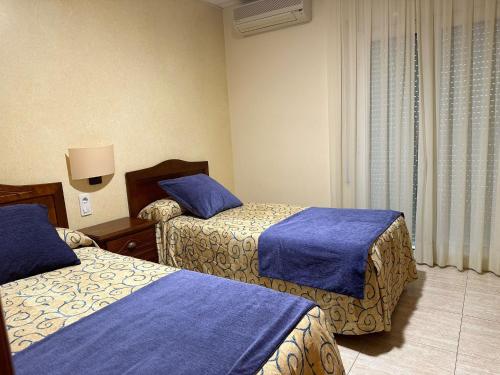 Habitación de hotel con 2 camas con sábanas azules en Hotel Sancho en Hospitalet de l'Infant
