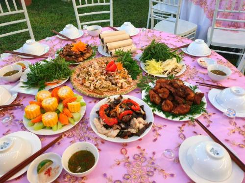 uma mesa rosa com pratos de comida em Ngòi Xanh Ecolodge (Bungalow - Restaurant - Coffee) em Tuyên Quang