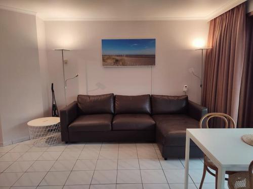 a living room with a brown couch and a table at 4-persoons appartement met een mooi uitzicht in De Panne