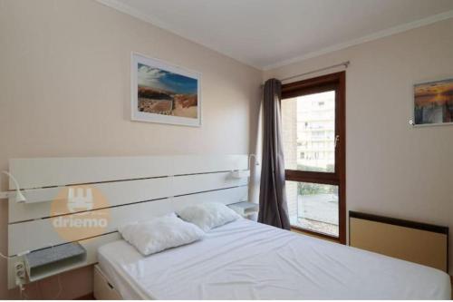um quarto com uma cama branca e uma janela em 4-persoons appartement met een mooi uitzicht em De Panne