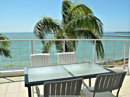 a table and chairs on a balcony with the ocean at Water View Apartment- Pool Gym Parking- Simply Stunning in Urangan