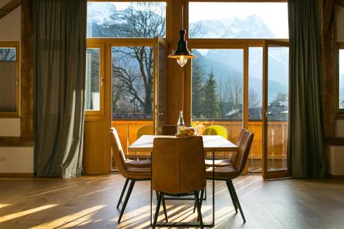 una sala da pranzo con tavolo e sedie e una grande finestra di Bio Ferienwohnungen im Lieblingsort 1868 a Garmisch-Partenkirchen