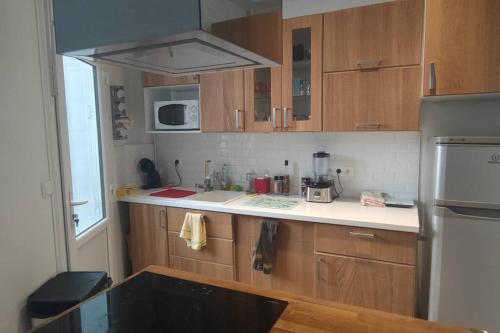 une cuisine avec des armoires en bois et un comptoir blanc dans l'établissement Studio 2 pièce charmant et calme, à Boulogne-Billancourt