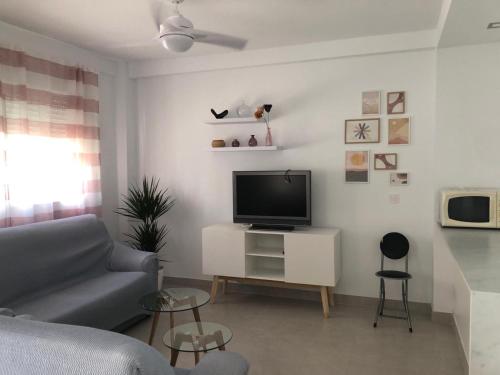 ein Wohnzimmer mit Sofa und Fernseher in der Unterkunft Apartamento muy cerca de la PLAYA LA ANTILLA in La Antilla