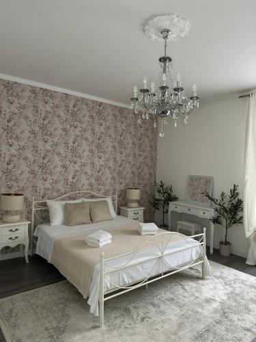 biała sypialnia z łóżkiem i żyrandolem w obiekcie Rooms Zana w Splicie