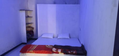 um pequeno quarto com uma cama num quarto branco em City yatra em Ujaim