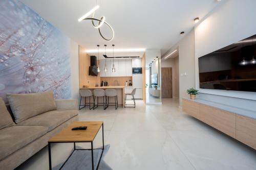 a living room and kitchen with a couch and a table at Apartament z wielkim tarasem Morska 2 Rewal 50m do morza in Rewal