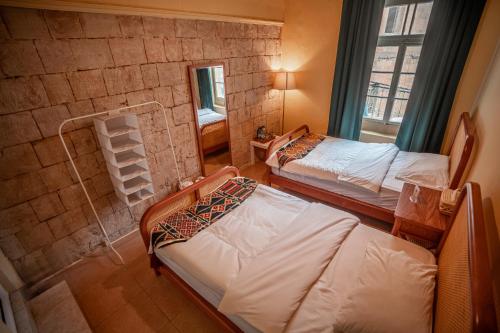 a bedroom with two beds and a brick wall at Jordan Heritage Madhafa in Al Salt