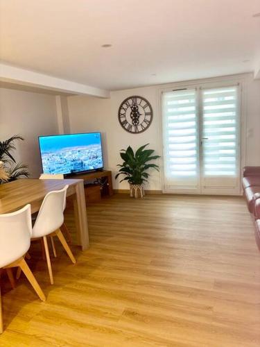 - un salon avec une table et une horloge murale dans l'établissement Maison chaleureuse proche Paris, à Châtillon