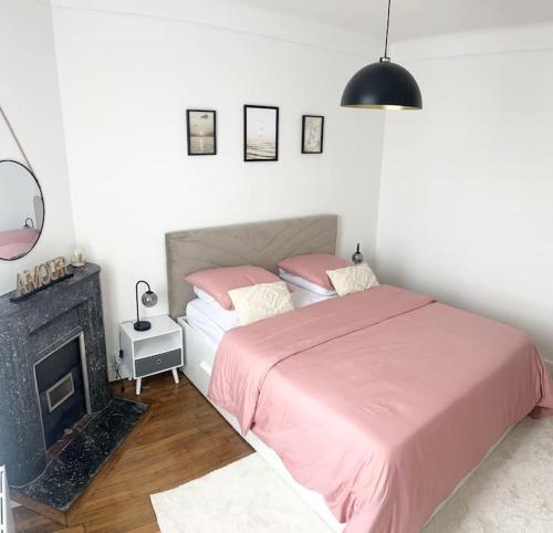 - une chambre avec un lit rose et une cheminée dans l'établissement Maison chaleureuse proche Paris, à Châtillon