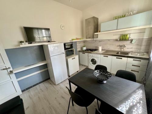uma pequena cozinha com uma mesa com cadeiras e um lavatório em Bilocale al mare em Rimini