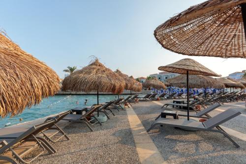 a group of chairs and straw umbrellas on a beach at Cumbalıca Beach Hotel in Cesme