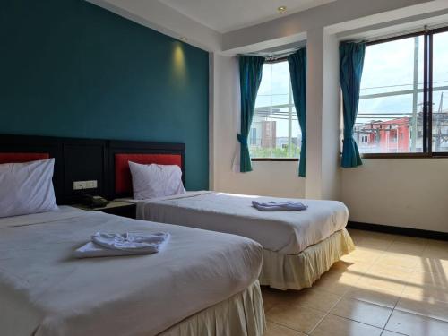 two beds in a room with blue walls and windows at Desa Phuket in Phuket Town