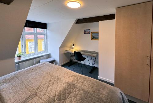 a bedroom with a bed and a desk and a window at Lejlighed med et eller to separate soveværelser in Ribe